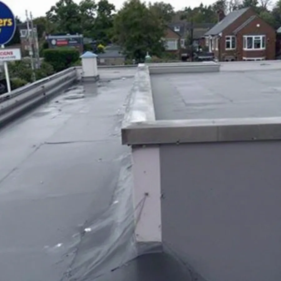 Flat roof where the membrane turns up a low parapet wall and terminates under a metal coping cap