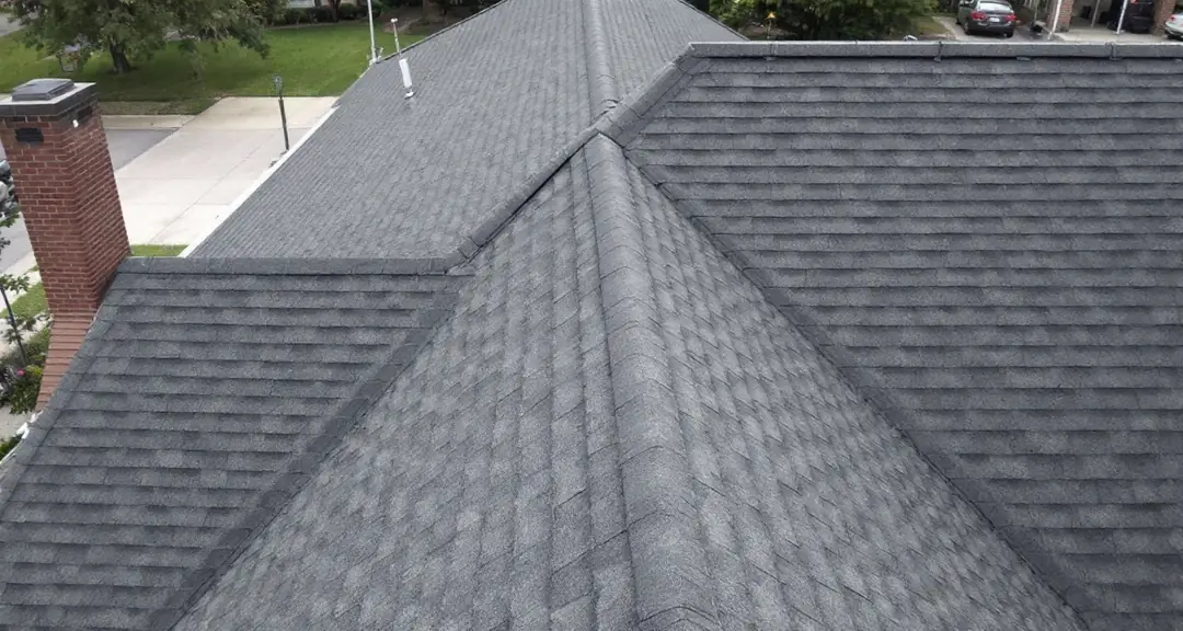 Residential asphalt shingle roof seen from above at an angle, with ridge, valley and vent pipes visible across the whole roof plane