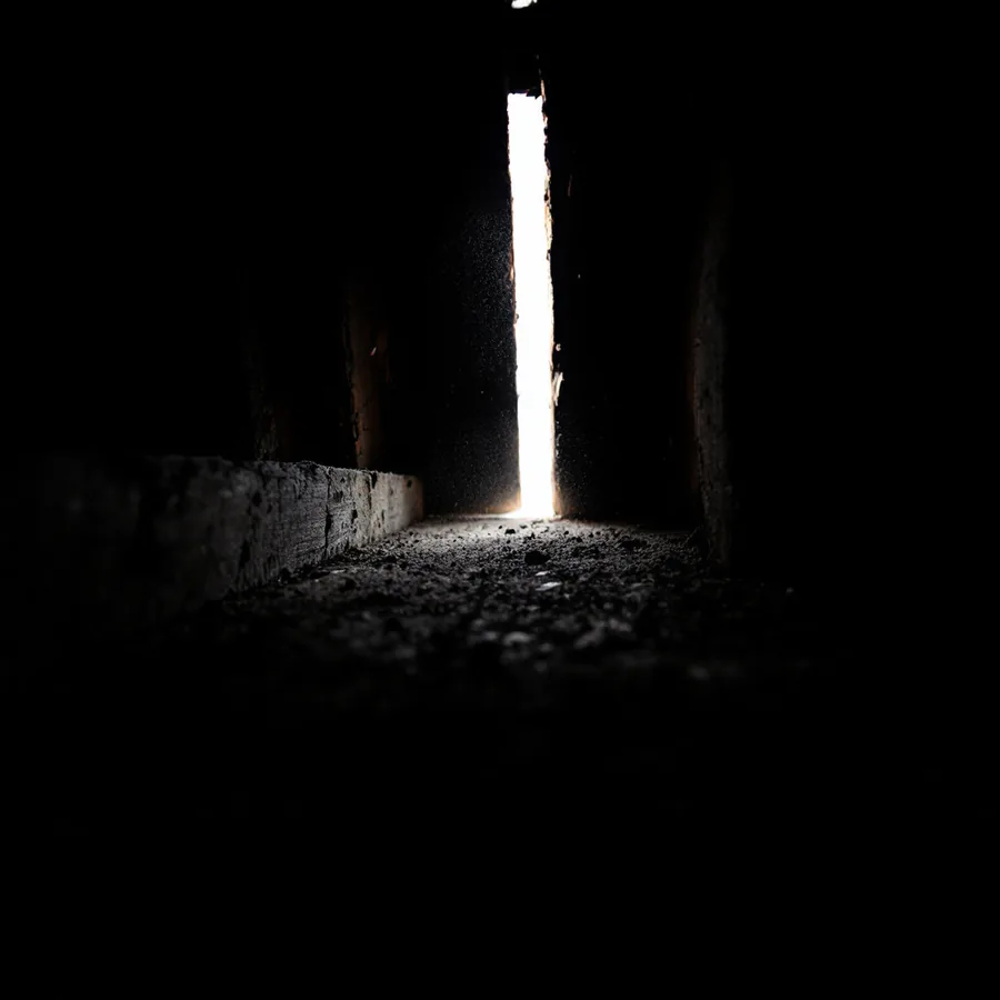 Thin shaft of daylight coming through a small gap in the roof decking inside a dark roof space