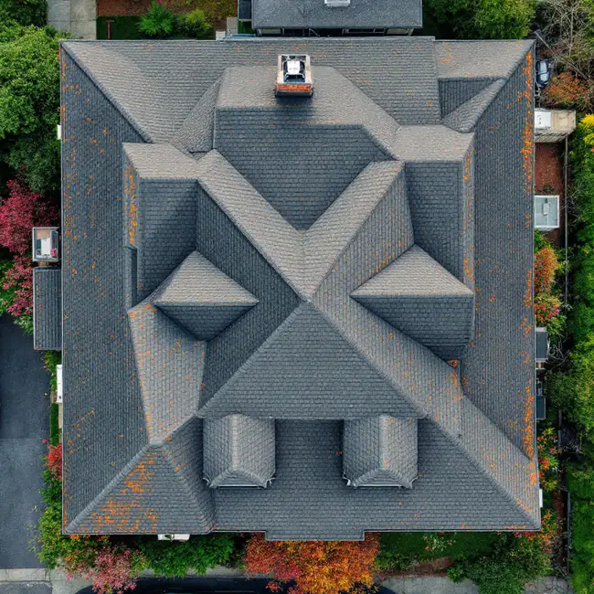 Aerial view of a complicated residential roof with many hips, valleys, dormers and a chimney