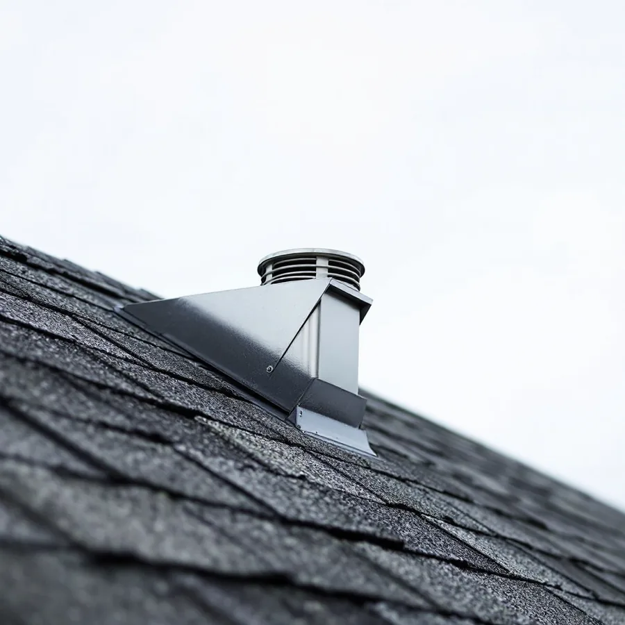 A ridge vent running along the top of an asphalt shingle roof, covered by ridge cap shingles